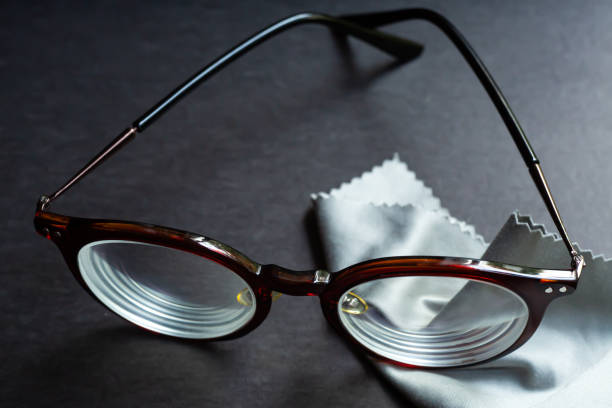 istock Brown shortsighted or nearsighted eyeglasses with microfibre cleaning cloths, On black background, Close up & Macro shot, Selective focus, Optical concept 1205266197