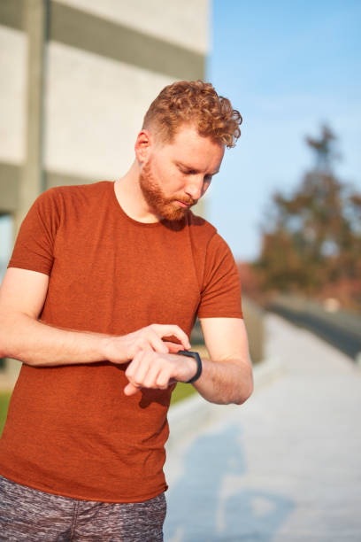 istock Young man using hand watch during exercising / stretching in urban park. 1205267872