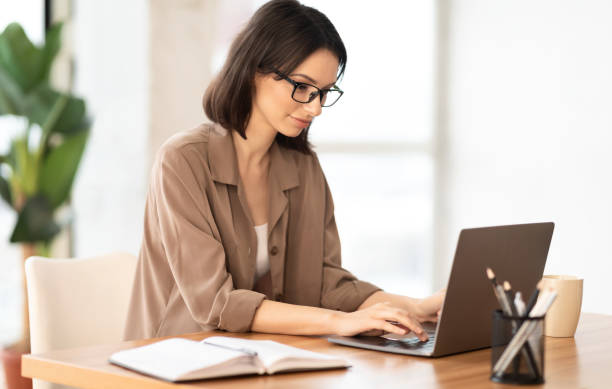 istock Portrait of smiling woman using laptop at workplace 1205268966