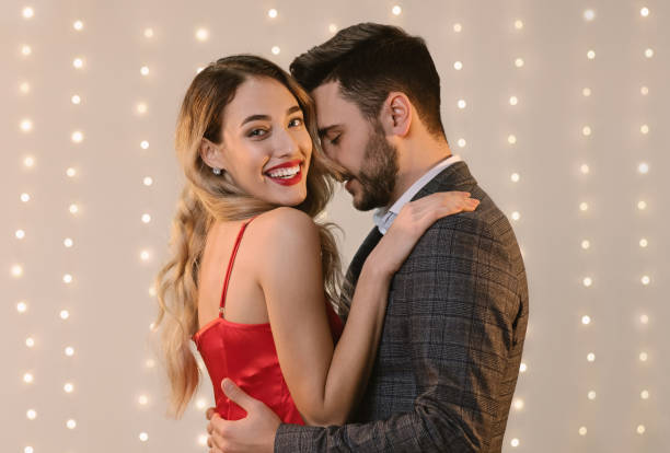 istock Attractive couple embracing and bonding while standing over beige background indoors 1205269672