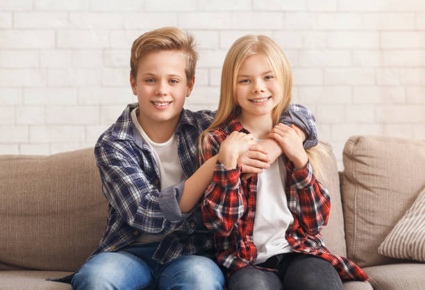 istock Cute Boy And Girl Hugging Sitting On Sofa At Home 1205272199