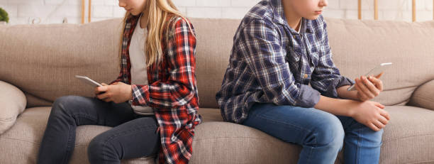 istock Boy And Girl Using Smartphones Sitting On Sofa, Cropped, Panorama 1205272238