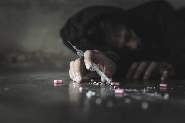 человеческая рука наркомана и шприц с наркотическим шприцем, лежащим на полу. концепция борьбы с наркотиками. - narcotic teenager cocaine drug abuse стоковые фото и изображения