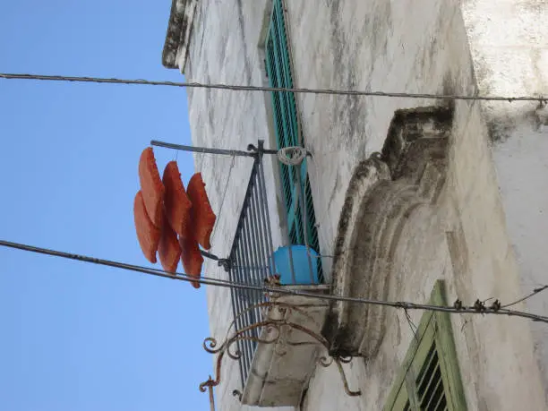 six red cushions hanging on a drying rack on a balcony in Polignano a Mare Italy