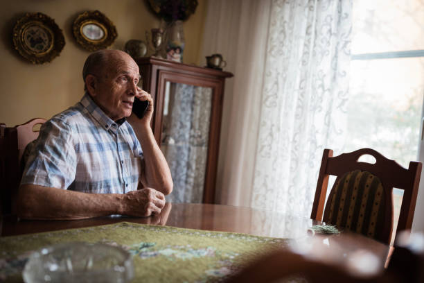 Cheerful senior man using mobile phone at home
