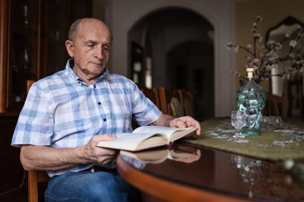 istock Senior man reading book indoors 1205276037