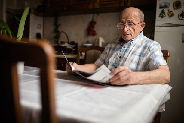 Senior man reading daily newspapers at home