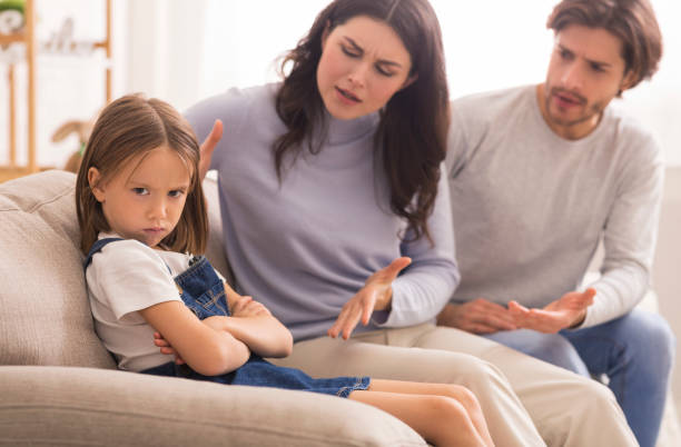 Annoyed Parents Scolding Their Little Daughter For Her Behaviour At Home Naughty Kid. Annoyed Parents Scolding Their Little Daughter For Her Behaviour While Sitting Together On Couch At Home scolding stock pictures, royalty-free photos & images