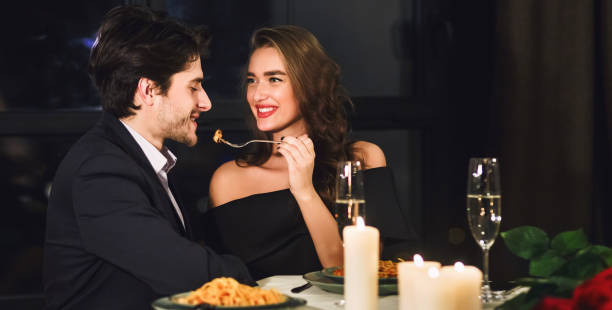 istock Loving Couple Having Date Feeding Each Other In Restaurant, Panorama 1205277738