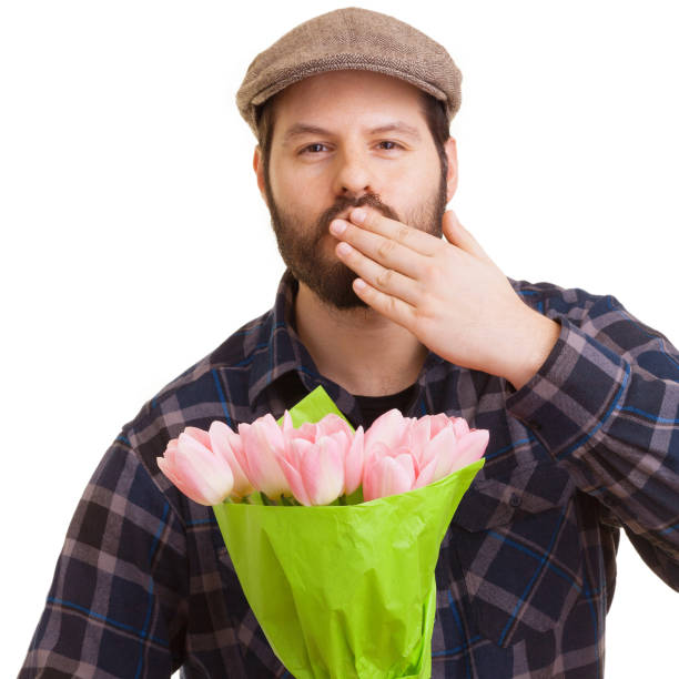 白い背景に孤立したピンクのチューリップの花束を持ち、キスを投げるひげを生やした若いハンサムな男。母の日、バレンタインデー、イースターと驚きのコンセプト。 - single flower flower mothers day easter ストックフォトと画像