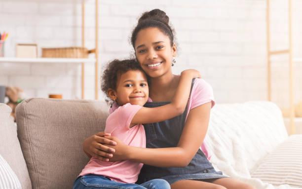 istock Happy african american sisters embracing at home 1205278002