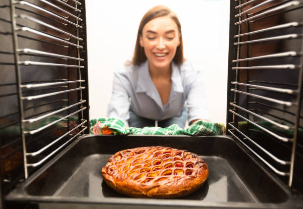 Housewife preparing pie in oven at home
