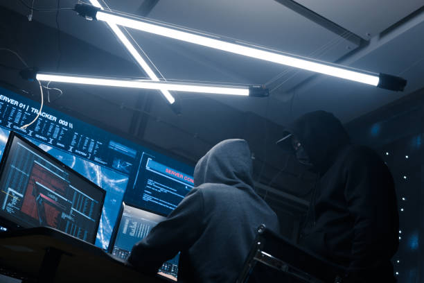 istock Two hackers look at the monitor and discuss new software code for breaking the security system 1205278178