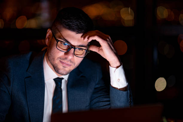 istock Businessman Working On Laptop Thinking Sitting In Office At Night 1205278241