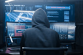 Computer hacker coding on keyboard on a background of monitors.