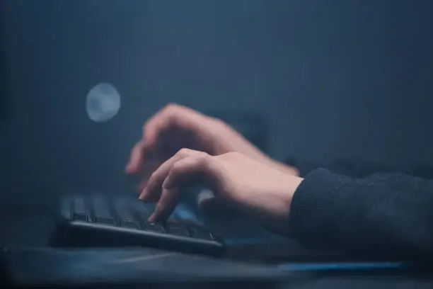 Photo of Close-up of the hacker's hands coding on laptop, typing program code on the keyboard.
