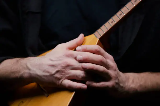 Close-up of balalaika in male hands on a dark background.