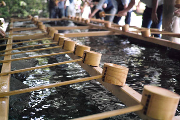 Chozuya ladels lined up for people to wash their hands and mouth Ise, Japan - 27/6/2019: Chozuya ladels with blurred people in the background washing their hands before entering Ise Jingu mie prefecture photos stock pictures, royalty-free photos & images