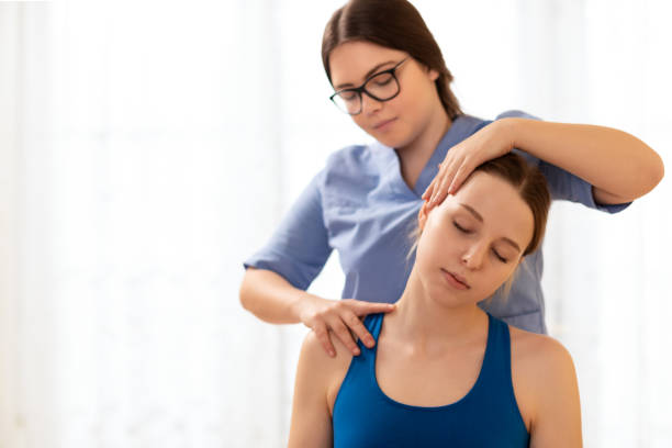 Female physiotherapist or a chiropractor adjusting patients neck. Physiotherapy, rehabilitation concept. White background front view with copy space. Female physiotherapist or a chiropractor adjusting patients neck. Physiotherapy, rehabilitation concept. White background front view with copy space. osteopath photos stock pictures, royalty-free photos & images