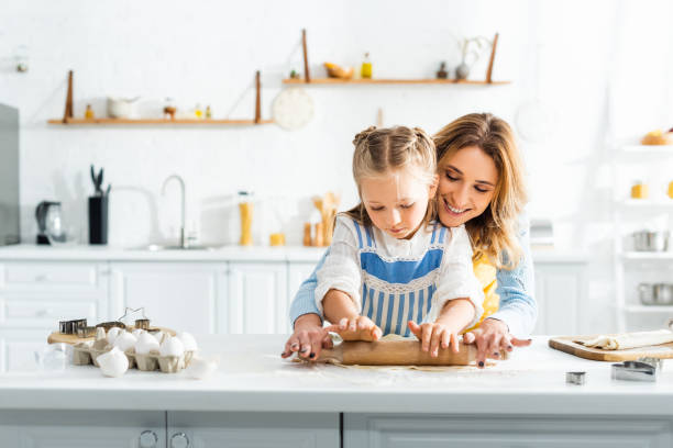 istock smiling mother and cute daughter rolling dough on table 1205281251