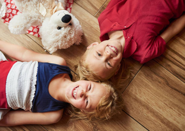 kids lying on floor in cozy nursery. Boy and girl holding flashlights in hands. Children play in a makeshift tent in the nursery.