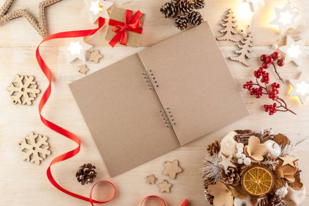 istock Open notebook in dark paper on a wooden table surrounded by handmade Christmas decorations 1205281513