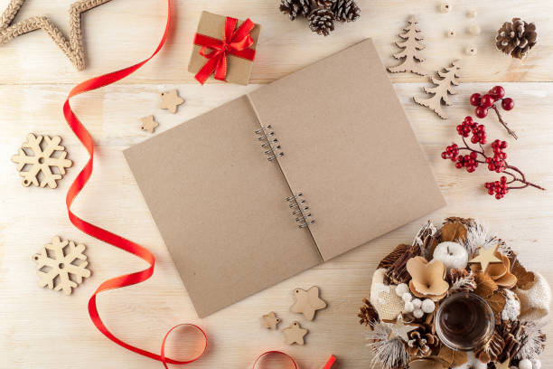 istock Open notebook in dark paper on a wooden table surrounded by handmade Christmas decorations 1205281514