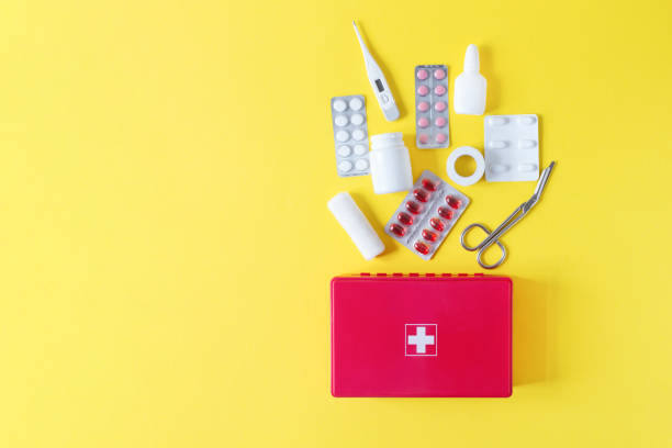 パステルイエローの背景に緊急トップビューのための医療機器や薬と応急処置キットの赤い箱。 - bandage sheers ストックフォトと画像