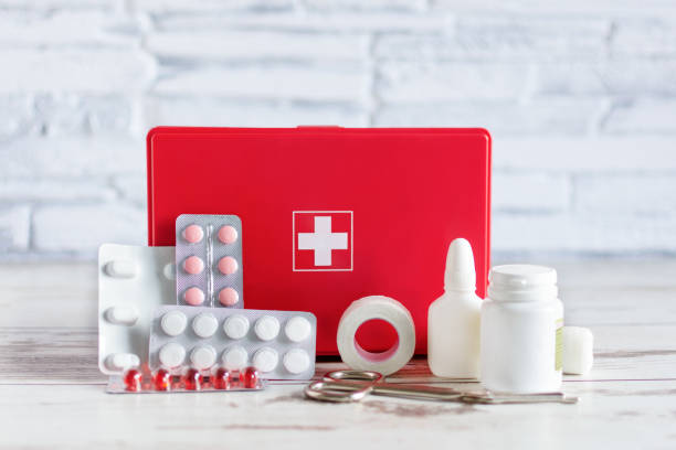 First aid kit red box with medical equipment and medications for emergency on white wooden background. First aid kit red box with medical equipment and medications for emergency on white wooden background over brick wall. first aid kit wall stock pictures, royalty-free photos & images