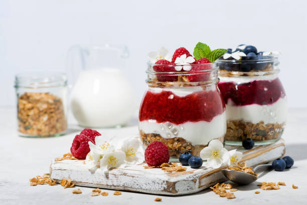 istock desserts with granola, berry and fruit puree in jars on white table, closeup 1205284216