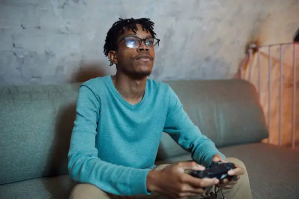 Portrait of smiling African-American man playing videogames via gaming console, copy space