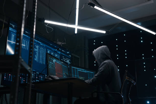 istock View from the ground of a computer hacker coding on keyboard on a background of monitors. 1205286021