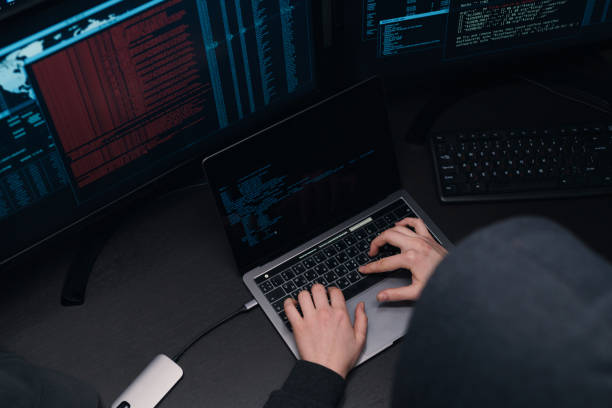 istock Top view of a computer hacker coding on laptop on a background of monitors. 1205286068
