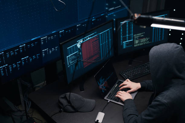 istock Top view of a computer hacker coding on laptop on a background of monitors. 1205286081