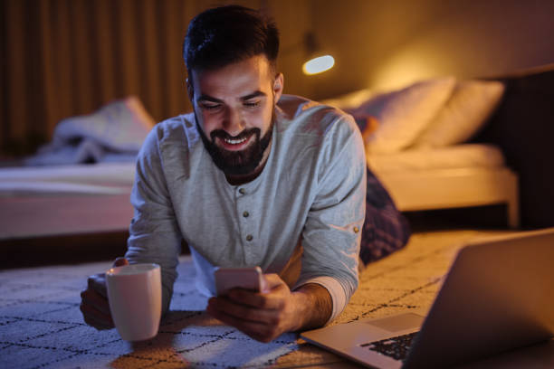 istock Handsome bearded man using phone in bedroom at night 1205287075