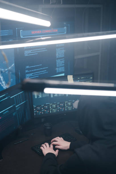istock Top view of a computer hacker coding on laptop on a background of monitors. 1205287353