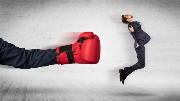 istock Arm with boxing gloves hits office worker concept 1205288170