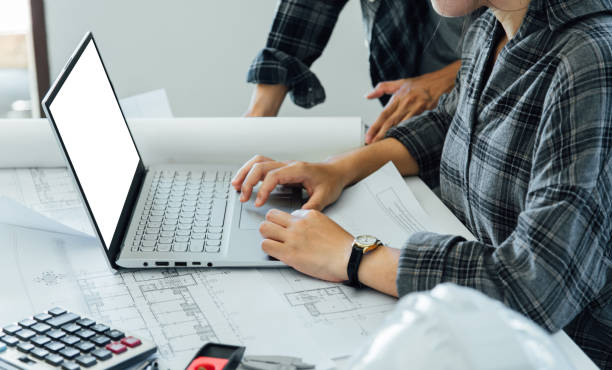 istock Concept architects, equipment architects, Working On a blank mockup white laptop with a blueprint and Model in the office Selective Focus 1205288969