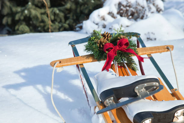 istock Vintage skates wreath red bow and sled in snow 1205289835