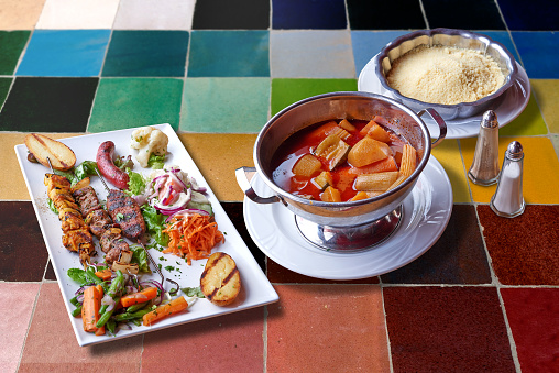 Delicious traditional moroccanCouscous and grilled meats on colorful mosaic table