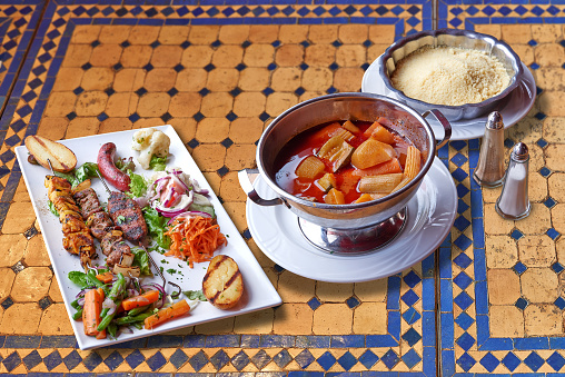 Delicious traditional moroccan Couscous and grilled meats on colorful mosaic table