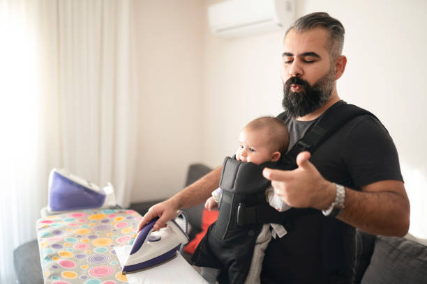 istock Young father ironing clothes and carrying his little daughter 1205291936
