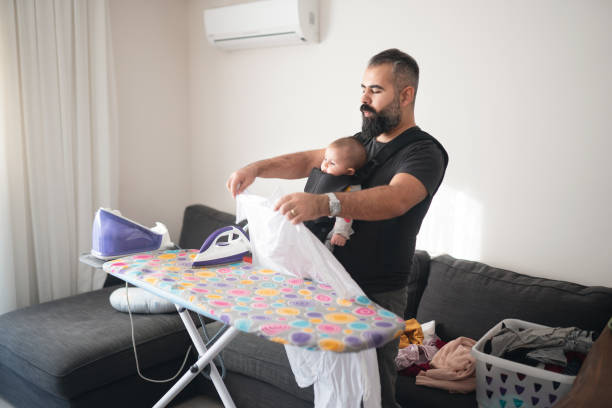 istock Young father ironing clothes and carrying his little daughter 1205291943