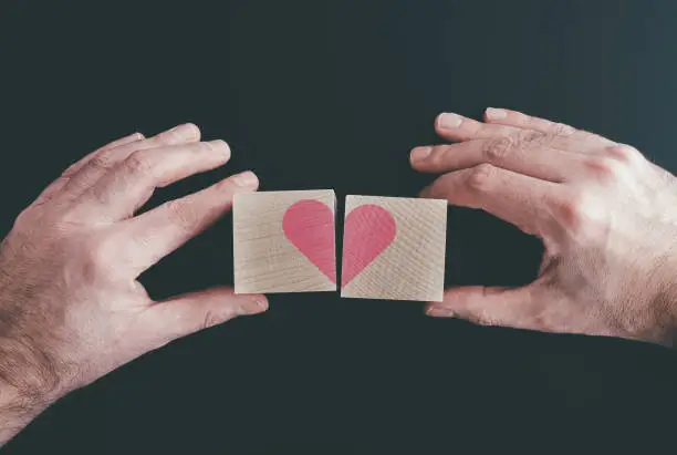 hands connecting or disconnecting woodenblocks with red heart, love or broken heart concept