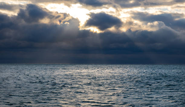 istock blue dark stormy clouds above the sea, the sun rays breaks through the clouds 1205296686