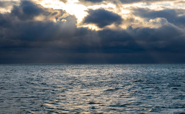 istock blue dark stormy clouds above the sea, the sun rays breaks through the clouds 1205296773