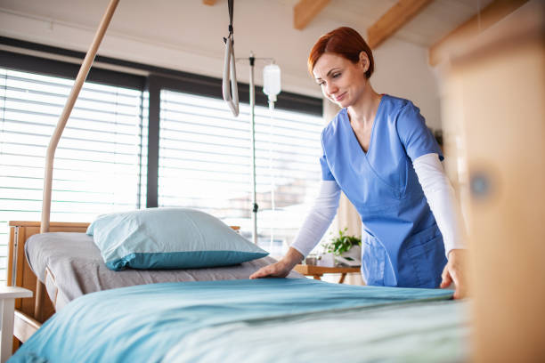 Portrait of female nurse or housekeeping staff changing sheets in hospital. A portrait of female nurse or housekeeping staff changing sheets in hospital. hospital bed sheets stock pictures, royalty-free photos & images