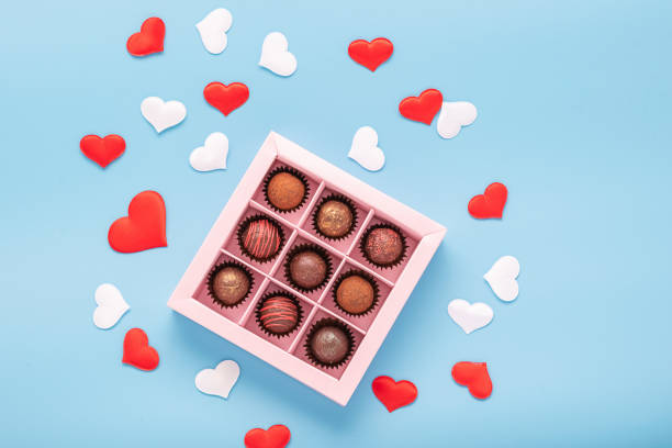istock Chocolate truffle candies in a box on a blue background with valentines. Valentines day concept festive food gifts. 1205299970