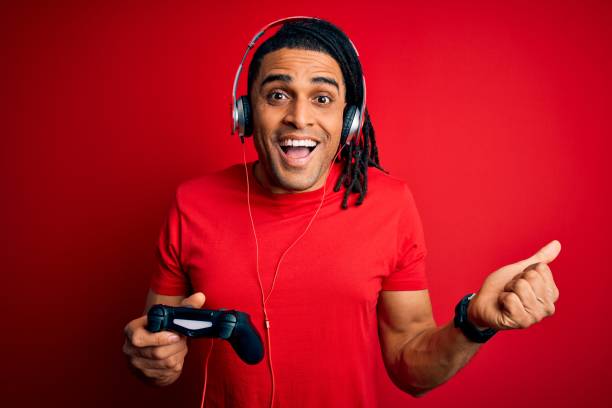 istock African american man with dreadlocks playing video game using joystick and headphones screaming proud and celebrating victory and success very excited, cheering emotion 1205300552