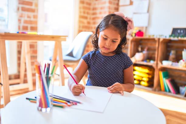 istock Beautiful toddler girl drawing cute draw using colored pencils at kindergarten 1205301749